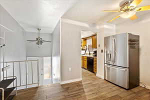 Kitchen featuring stainless steel refrigerator with ice dispenser, a ceiling fan, dishwasher, light wood-style floors, and a textured ceiling