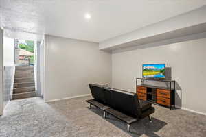Living room with carpet floors, baseboards, recessed lighting, and stairway