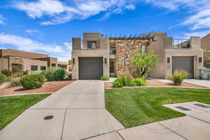 Southwest-style home featuring stucco siding, concrete driveway, stone siding, and a front yard
