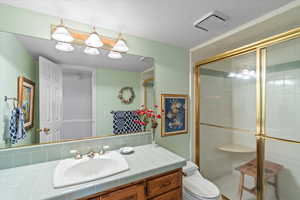 Bathroom with a stall shower, toilet, and vanity
