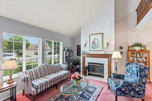 Carpeted living area with high vaulted ceiling and a fireplace
