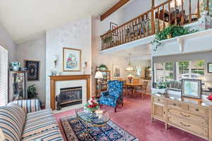 Carpeted living area featuring healthy amount of natural light, a tiled fireplace, and high vaulted ceiling