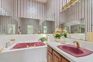 Primary bathroom with a towering ceiling, a garden tub, wallpapered walls, vanity, and tile patterned flooring