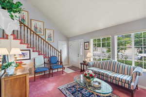 Carpeted living area featuring stairway and high vaulted ceiling