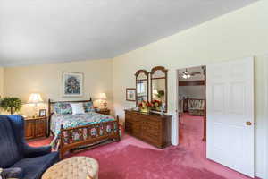 Primary bedroom with carpet floors, a textured ceiling, and lofted ceiling