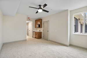 Unfurnished living room featuring light colored carpet and a ceiling fan