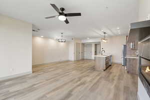 Unfurnished living room featuring recessed lighting, light wood-type flooring, a ceiling fan, a glass covered fireplace, and a chandelier