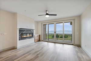 Unfurnished living room with a mountain view, a high end fireplace, light wood-type flooring, and a ceiling fan