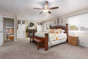 Bedroom with carpet flooring, a fireplace with flush hearth, ceiling fan
