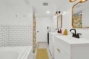 Bathroom with two vanities, tiled bath, a shower with curtain, tile patterned flooring, and recessed lighting