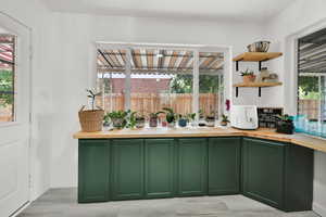 Kitchen with green cabinets, butcher block counters, and open shelves