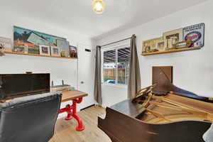 Home office featuring wood finished floors, a textured ceiling, and baseboards