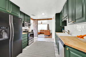 Kitchen featuring stainless steel appliances, green cabinets, a sink, and a textured ceiling