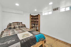 Bedroom with wood finished floors, baseboards, recessed lighting, and a textured ceiling