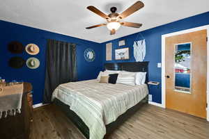 Bedroom with wood finished floors, baseboards, a textured ceiling, and a ceiling fan