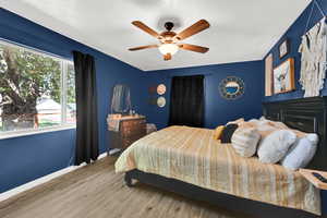 Bedroom featuring a textured ceiling, wood finished floors, baseboards, and a ceiling fan