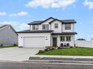 View of front of property featuring concrete driveway, covered porch, and a garage