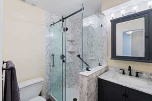 Bathroom with a shower stall, toilet, and vanity