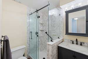 Full bath featuring a stall shower, toilet, and vanity