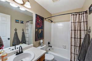 Full bath with vanity, toilet, and shower / tub combo with curtain