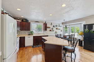 Kitchen with white appliances, a sink, a kitchen island, a kitchen bar, and ornamental molding