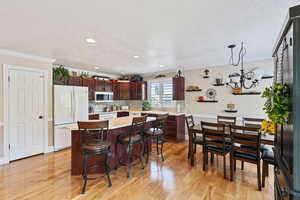 Kitchen with freestanding refrigerator, a textured ceiling, light countertops, crown molding, and a chandelier