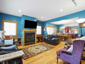Living room with wood finished floors, a fireplace, a chandelier, and recessed lighting