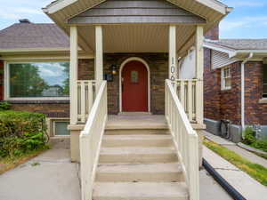 Doorway to property with brick siding and roof with shingles