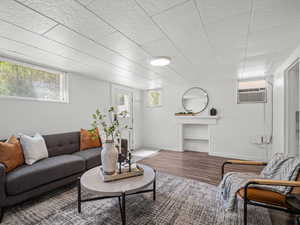 Living area with wood finished floors and a wall mounted air conditioner