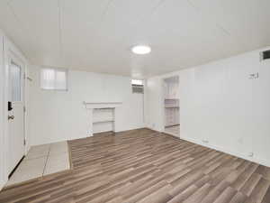 Below grade area with a wall mounted air conditioner, baseboards, and wood finished floors