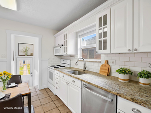 Kitchen with white appliances, a sink, glass insert cabinets, white cabinetry, and backsplash