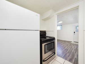 Kitchen with stainless steel electric stove, freestanding refrigerator, and wood finished floors