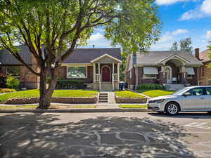 View of front facade with brick siding, a front yard, and a shingled roof
