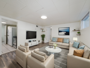 Living room featuring wood finished floors, stacked washing maching and dryer, and visible vents