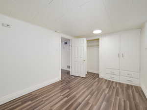Unfurnished bedroom with wood finished floors, a closet, baseboards, and visible vents