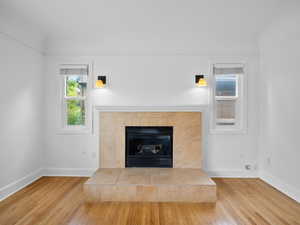 Interior details with baseboards, a tiled fireplace, and wood finished floors
