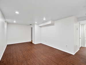 Finished basement with visible vents, baseboards, recessed lighting, and dark wood-type flooring