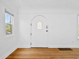Foyer with light wood-style floors, visible vents, and baseboards