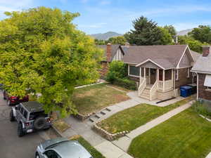 View of front of home with roof with shingles, a front lawn, a mountain view, a chimney, and brick siding