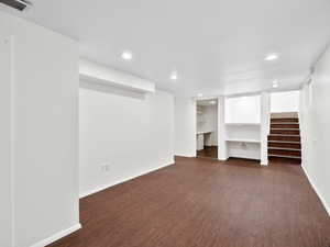 Finished basement featuring dark wood-type flooring, visible vents, baseboards, and recessed lighting