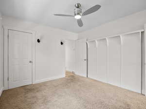 Unfurnished bedroom featuring carpet, a closet, baseboards, and a ceiling fan
