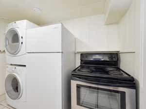 Laundry area with tile patterned flooring, stacked washing maching and dryer, and laundry area