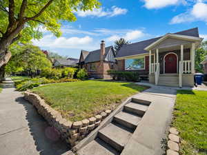 View of front of property with brick siding, a front yard, and roof with shingles