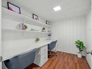 Office area featuring built in desk and dark wood finished floors