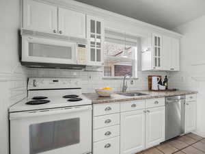 Kitchen with white appliances, glass insert cabinets, white cabinetry, tasteful backsplash, and a textured ceiling