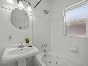 Bathroom featuring a combined bath / shower with jetted tub and a sink