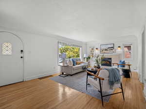 Living area with a tiled fireplace, wood-type flooring, and a textured ceiling