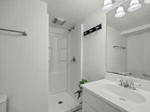 Bathroom featuring a stall shower, vanity, and a textured ceiling