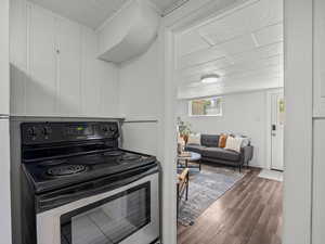 Kitchen featuring stainless steel range with electric cooktop, wood finished floors, and white cabinets