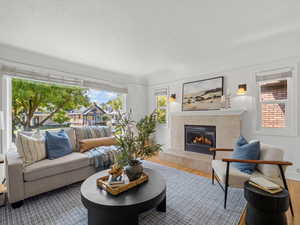 Living room featuring a tile fireplace, a textured ceiling, and wood finished floors